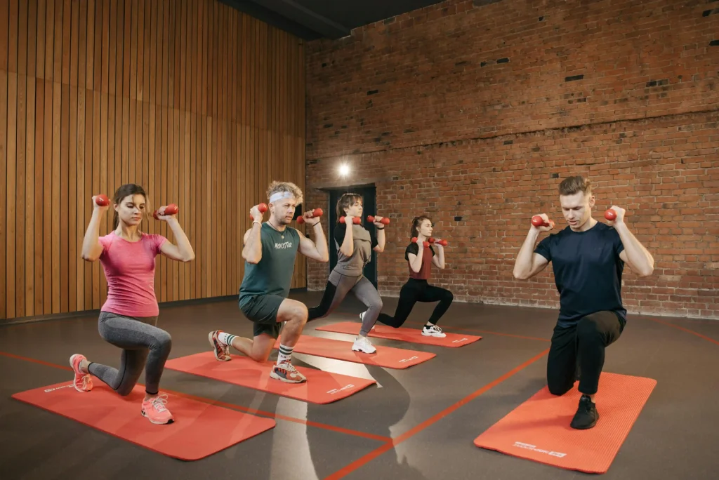 A diverse group of individuals exercising on mats in a gym, showcasing teamwork and fitness under the guidance of the best personal trainer.